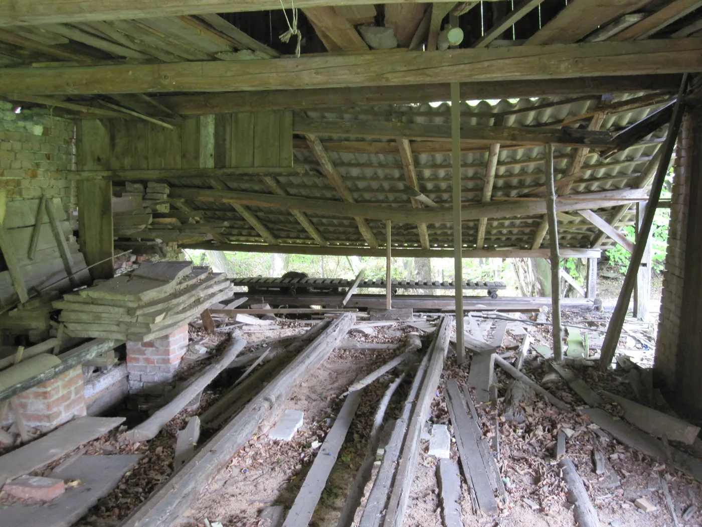 The inside of a collapsing roof, with broken beams and rubble on the floor