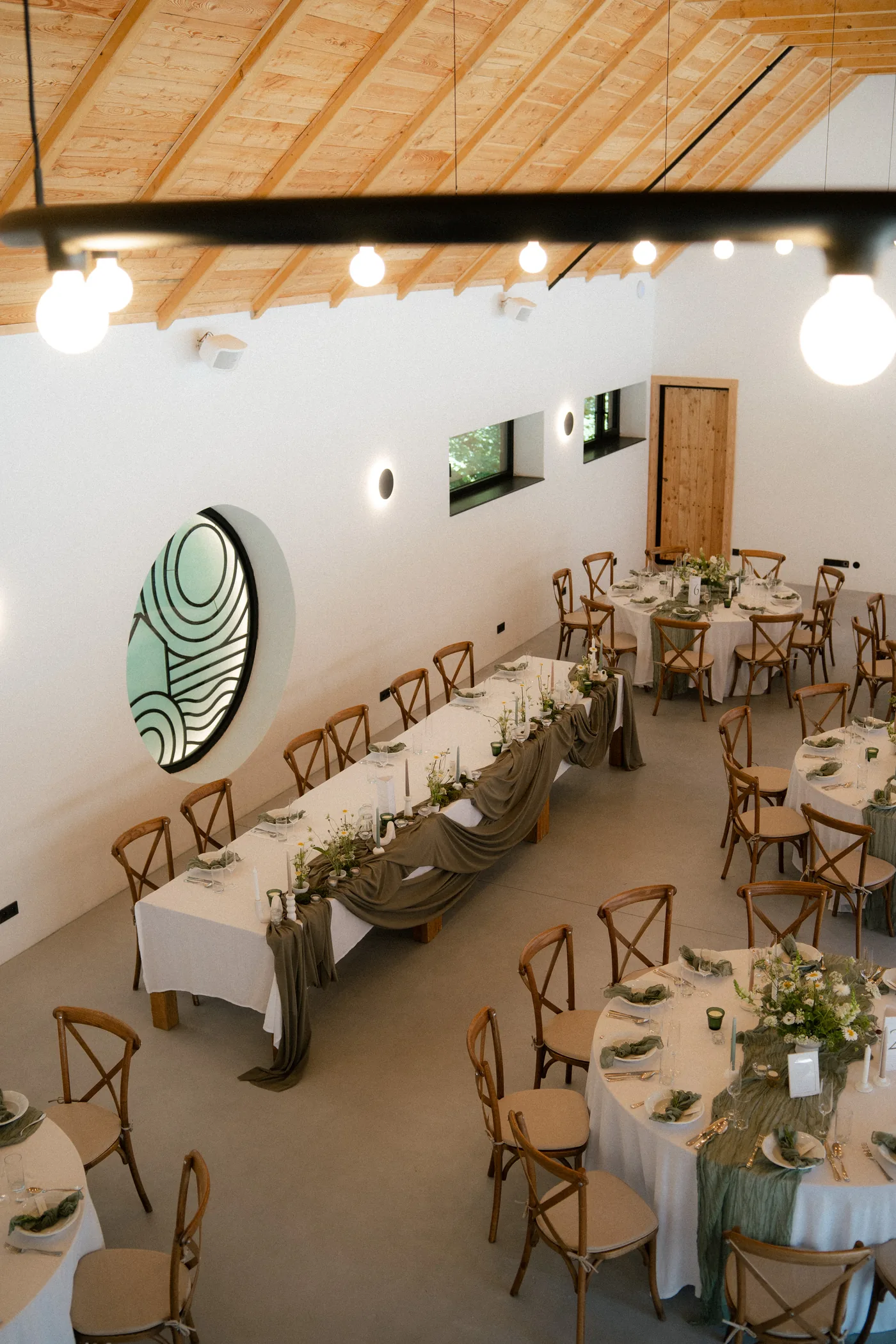 The hall seen from above, with one long table and round tables set for dinner