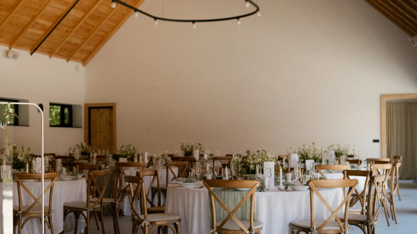 The barn hall with its timber roof, round tables and festoon lighting