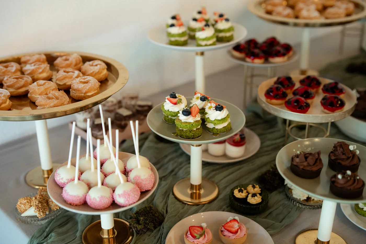 A dessert table laid out on a long table with cakes and candles