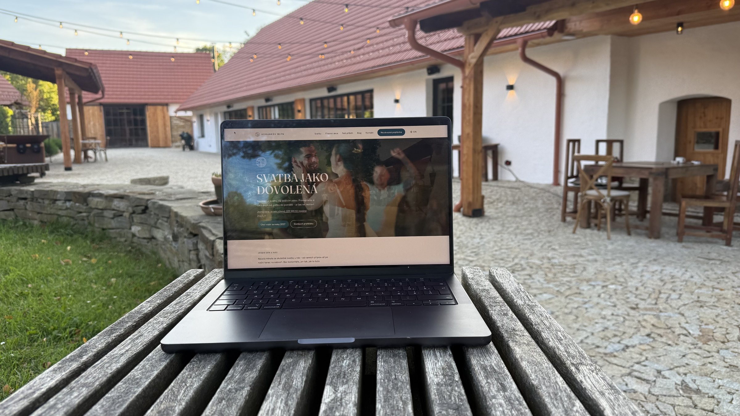 Notebook na lavici na nádvoří Kománkova mlýna, na obrazovce stránka s cenou svatebního víkendu